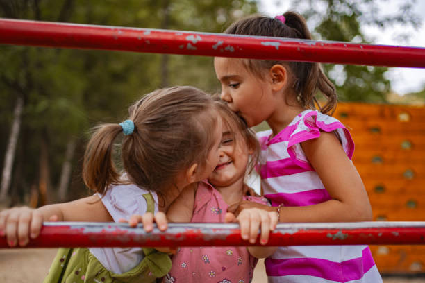 A mother enjoys playful moments with her twin daughters at a park, fostering joy and connection among them.