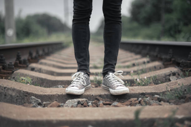 Hipster man in black jeans pants and grey sneakers on railway