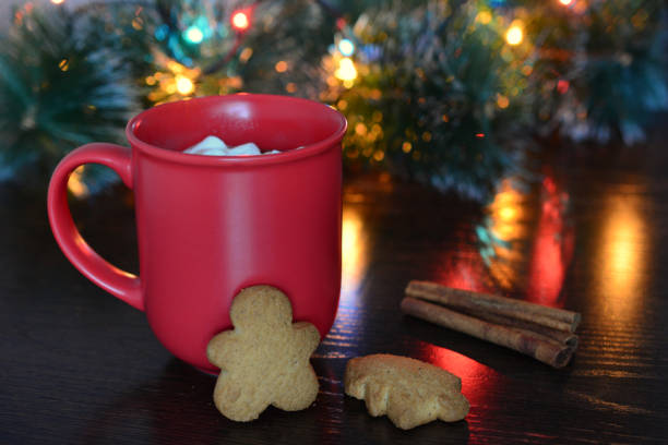 a red cup with a cookie next to a christmas tree with lights