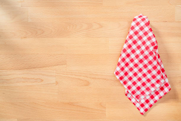 Flat lay of an empty wooden table with checkered tablecloth at the right. Copy space