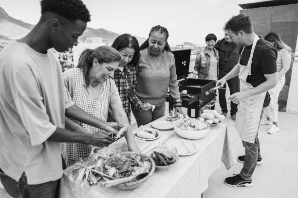 istock Multi generational people doing barbecue at home's rooftop - Multiracial friends having fun eating and cooking together during weekend day - Black and white editing - Main focus on african woman face 2167381208