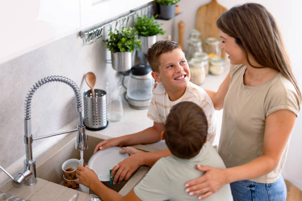 istock Mother supervising boys washing dishes in kitchen 2167387093