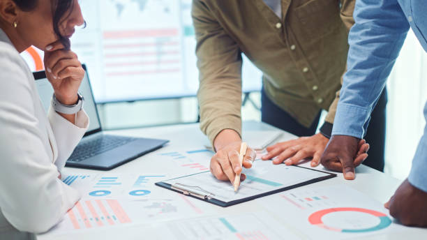 Close up of a multiethnic team of developers pointing to a graph with marketing data analysis.