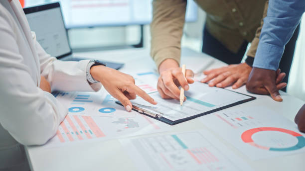 istock Close up of a multiethnic team of developers pointing to a graph with marketing data analysis. 2167387229