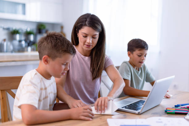 istock Mom assisting one child while another is using a laptop 2167387234
