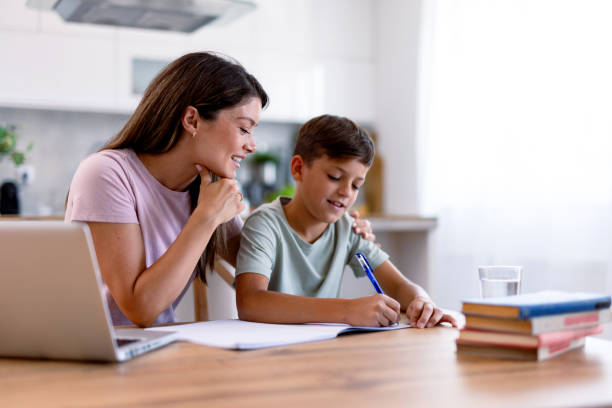 istock Woman tutors boy at kitchen table during homework 2167387472