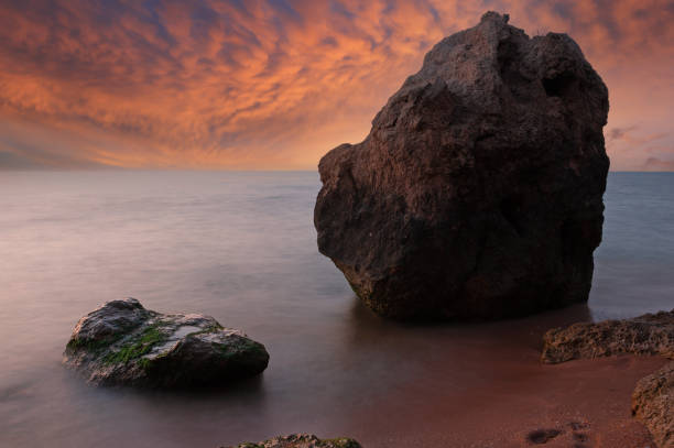 Evening landscape with stones in sea against sunset sky background