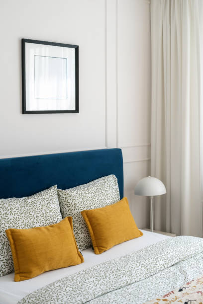 istock Cozy bedroom with a blue headboard and decorative pillows in a well-lit space 2167388540