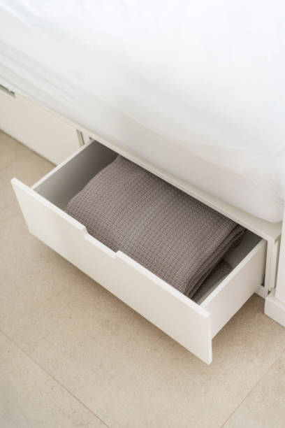 istock Neatly folded gray blanket stored in a white bed drawer in a modern bedroom setting 2167388541