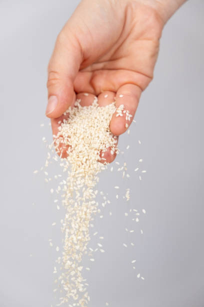 istock Hand pouring white sesame seeds on gray background 2167388668