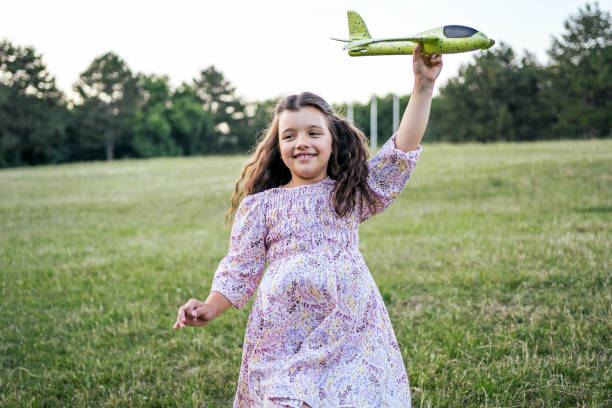 Beautiful little girl playing with toy airplane in the park