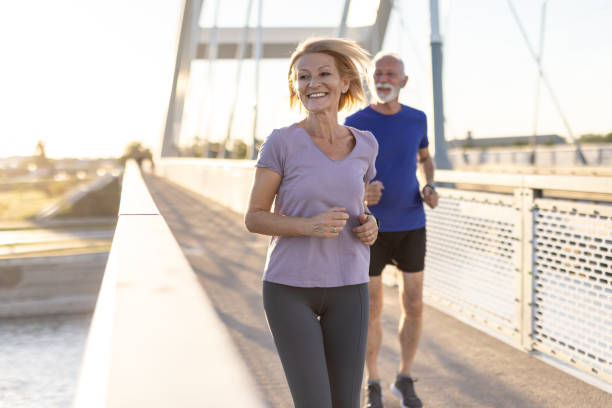 istock Elderly couple joyfully running together on a bridge under sunset. 2167395050