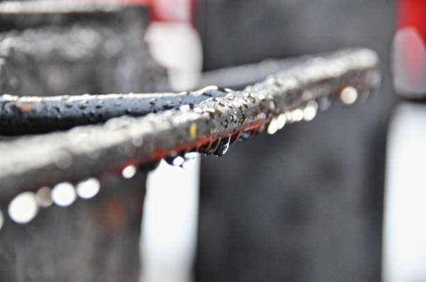 Water droplets hang from a rusty metal railing