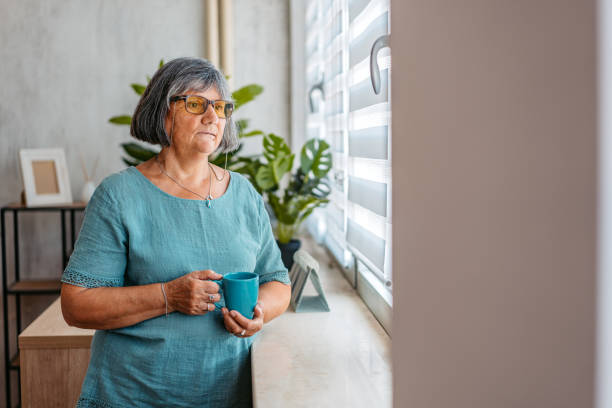 istock Senior Woman Looking Out The Window And Drinking Coffee 2167398156