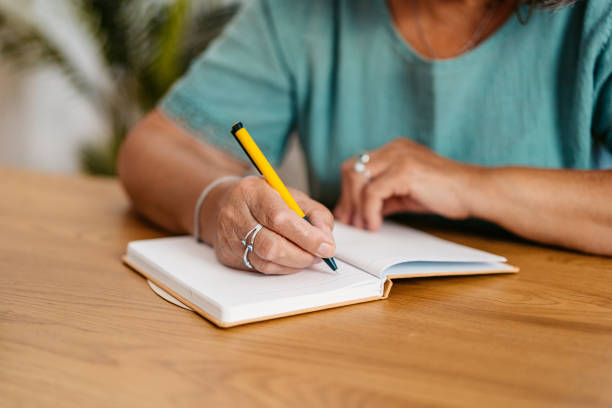 istock Senior Woman Writing In A Notebook At The Kitchen Table At Home 2167400230