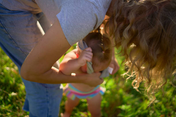 a  mother dresses toddler who screams, hates getting dressed
