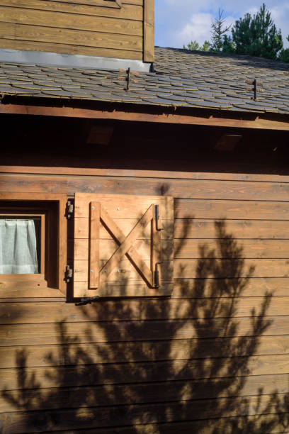 istock Tree shadow on wooden cabin facade 2167403018