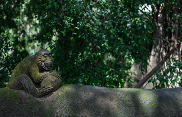 A tranquil monkey sculpture resting on a stone, surrounded by vibrant foliage.