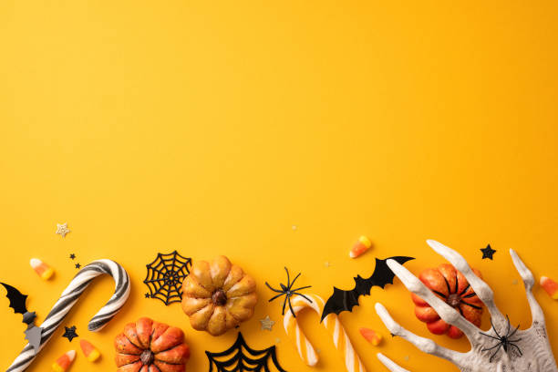 istock Halloween decorations arranged on an orange background featuring pumpkins, candy corn, bats, spider webs, and a spooky hand 2167406149