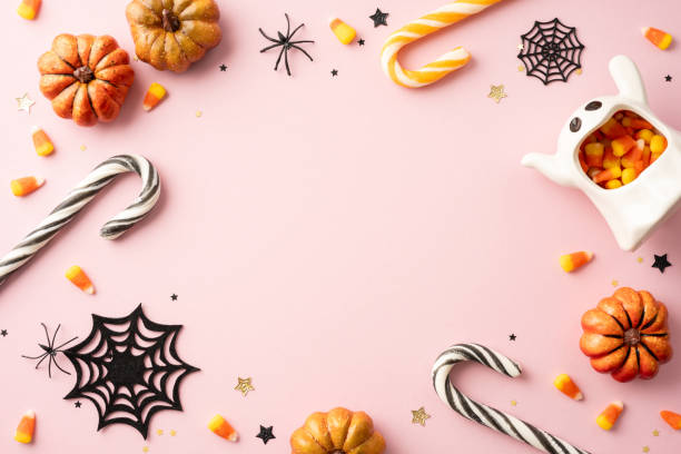 istock Halloween themed flat lay with pumpkins, candy corn, spiders, and a cute ghost decoration on a pink background 2167406152