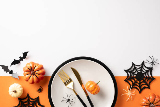 istock Festive Halloween table setting featuring pumpkins, spider webs, and cutlery on a white and orange background 2167406206