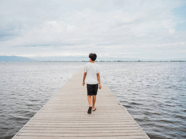 istock Boy walking on a wooden pier. 2167406659