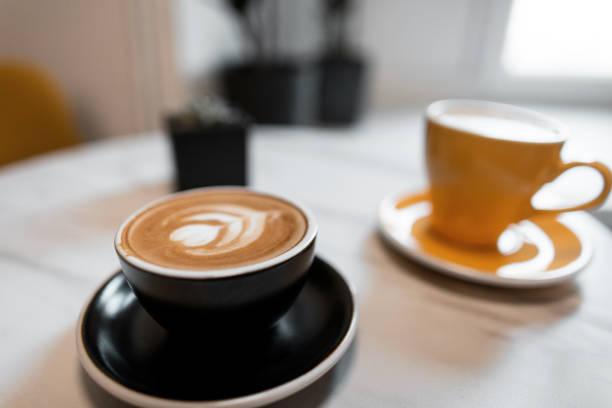 istock Two beautiful ceramic coffee cups stand on a table in a cafe with hot cappuccino and fragrant latte. Great morning coffee break. Close-up. 2167408880