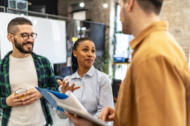 istock Three multi-ethnic coworkers standing together at an office, having a conversation. 2167410351