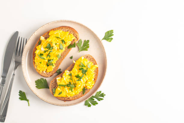 istock Scrambled eggs with green herbs on wheat-rye crispy toast. 2167412019
