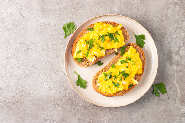 istock Scrambled eggs with green herbs on wheat-rye crispy toast. 2167412067
