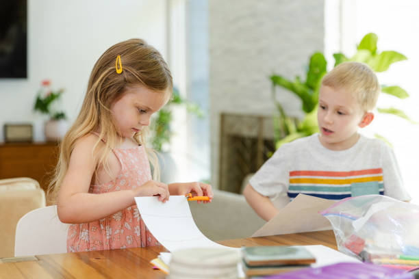 istock Elementary age boy supervises his sister while she cuts paper 2167412235