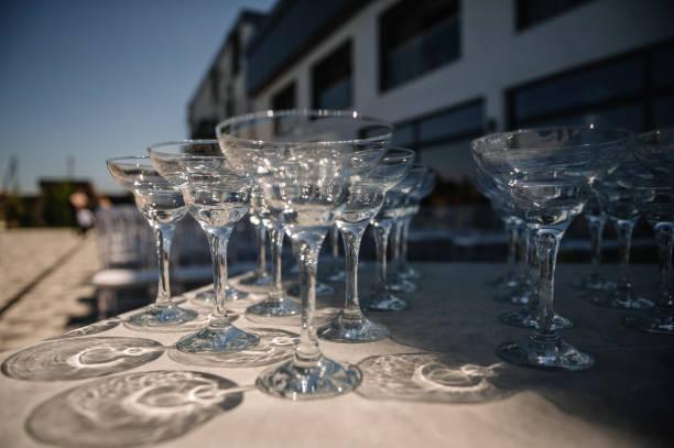 istock Empty wine glasses on a table in backyard. Table with empty wine glasses at a summer wedding. Festive wedding concept. Side view. 2167412550