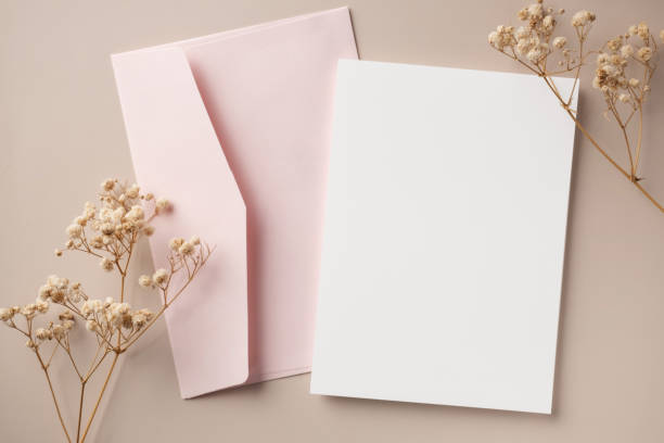 istock White blank greeting or invitation card and envelope with ceramic jar decoration on beige background. Mock up presentation. Flat lay. 2167412936