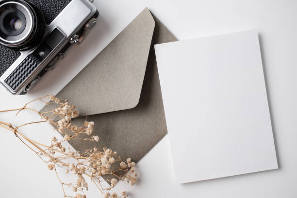 istock White blank greeting or invitation card with ceramic jar decoration and envelope on beige background. Mock up presentation. Flat lay. 2167413000