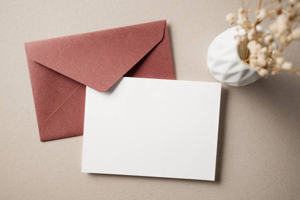 istock White blank greeting or invitation card with ceramic jar decoration and envelope on beige background. Mock up presentation. Flat lay. 2167413070