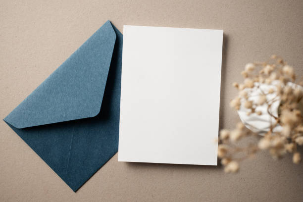 istock White blank greeting or invitation card with ceramic jar decoration and envelope on beige background. Mock up presentation. Flat lay. 2167413100