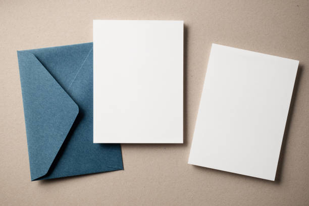 White blank greeting or invitation card and envelope on beige background. Mockup presentation. Flat lay.