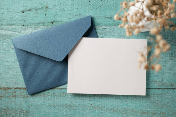 istock White blank greeting or invitation card and envelope on blue wooden background. Mockup presentation. Flat lay. 2167413180