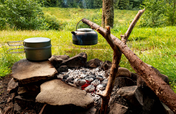 istock Making tea over an open fire in the forest. The kettle is hanging on a stick on the fire. 2167422134