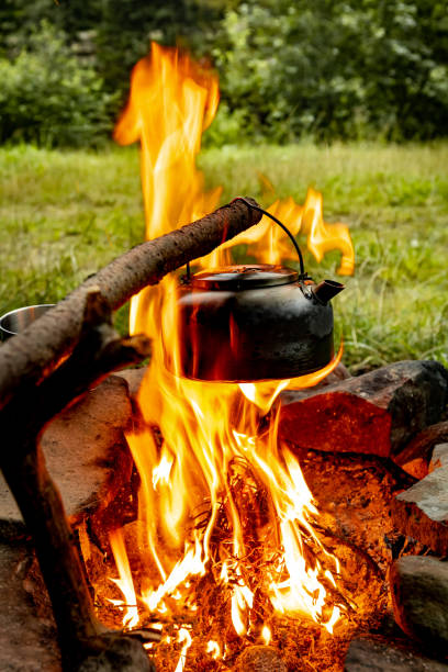 istock Making tea over an open fire in the forest. The kettle is hanging on a stick on the fire. 2167422149