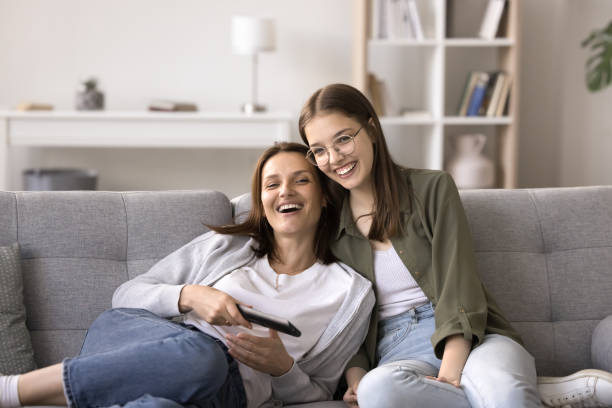 istock Joyful mother and daughter relax on sofa while watching TV 2167425278