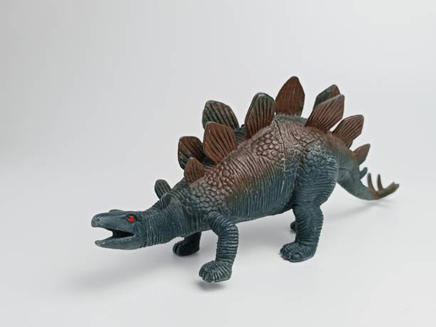 A boy interacts with plastic dinosaurs and action figures at a table, engaged in a fantasy world during creative solo play.