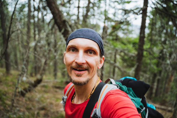 istock Man in hat smiling for a selfie with a backpack in natural landscape 2167434307