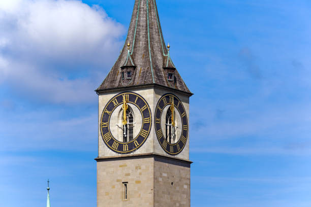istock Looking up clock tower with clock showing twelve o'clock at noon on a sunny summer day at Swiss town of Zurich. 2167436516