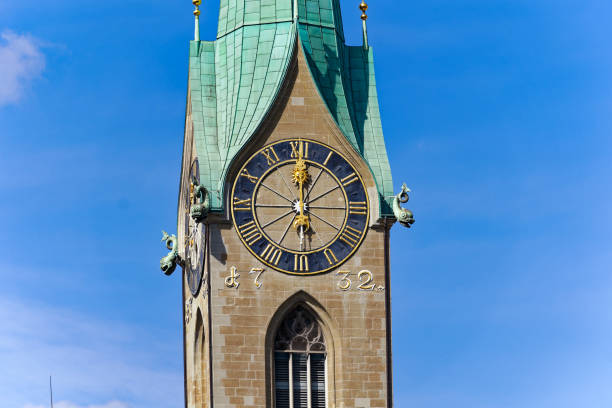 istock Looking up clock tower with clock showing twelve o'clock at noon on a sunny summer day at Swiss town of Zurich. 2167436518