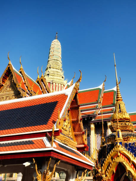 istock A captivating low-angle view of a Thai temple reveals its crimson rooftops, gilded embellishments, and a soaring white spire set against the backdrop of a pristine azure sky. 2167436643