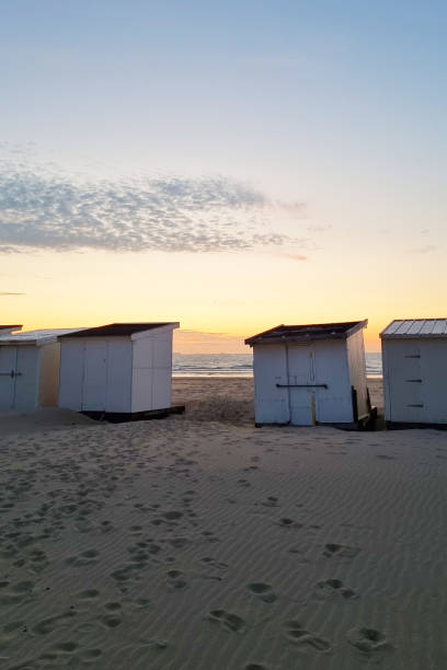 istock Tranquil Beach Sunset with White Beach Huts - Ideal for Summer Vacation Scenes 2167437535
