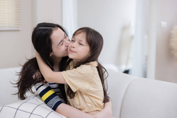 istock Two sisters hug each other with love on the couch 2167438338