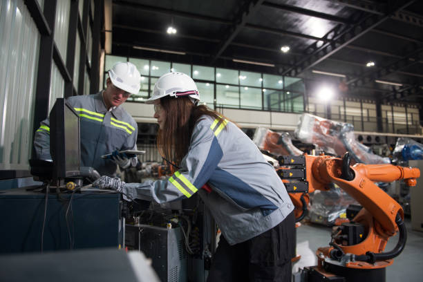 istock Engineer standing by robotic arm and operating machine in industry factory 2167442115
