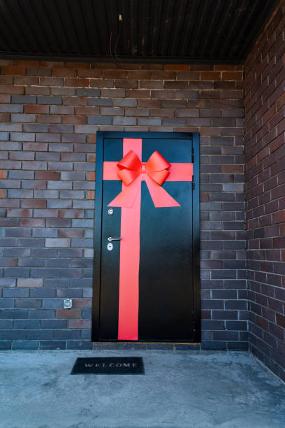 A striking contrast is formed by a black door with a bold red bow, creating a visually appealing sight. The doors design is eyecatching and adds a touch of elegance to the entrance